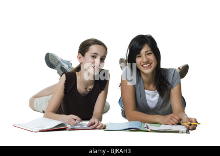 Deux jeunes filles se coucher à faire leurs devoirs Banque D'Images