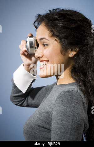 Profil de femme de prendre une photo avec appareil photo numérique smiling Banque D'Images