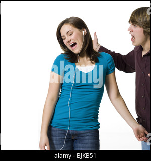 Girl listening to mp3 player with boy yelling Banque D'Images