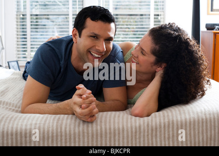 L'homme et la femme sur le lit se pelotonnant Banque D'Images