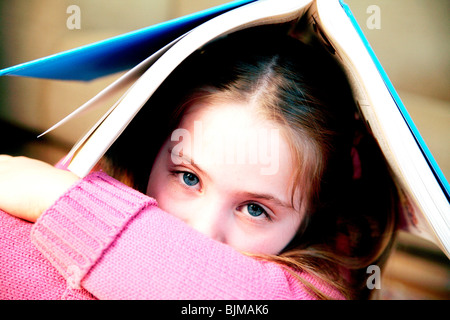 Jeune fille avec un livre sur la tête, ne voulant pas lire Banque D'Images
