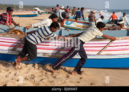 Les pêcheurs poussant leur bateau de pêche dans la mer, plage, Côte d'Malabarian Somatheeram, Malabar, l'état du Kerala, en Inde, en Asie Banque D'Images