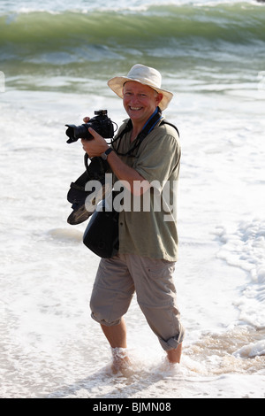 Photographe avec appareil photo dans l'eau sur la plage, côte de Malabar, Malabarian, l'État de Kerala, Inde, Asie Banque D'Images