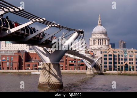 Le Millenium Bridge de Londres avec la pierre blanche de la Cathédrale St Paul en arrière-plan contraste avec un ciel gris foncé Banque D'Images