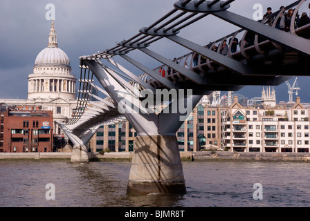 Le Millenium Bridge de Londres avec la pierre blanche de la Cathédrale St Paul en arrière-plan contraste avec un ciel gris foncé Banque D'Images