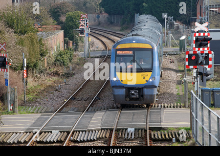L'approche d'un train de voyageurs de passage à niveau 'ouvrir' Banque D'Images