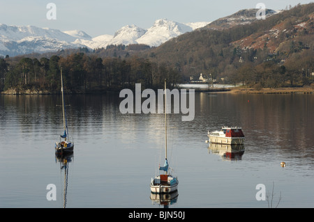 Yachts au Waterhead sur le lac Windermere dans le Lake District avec la neige sur les Langdale Pikes en arrière-plan. Banque D'Images