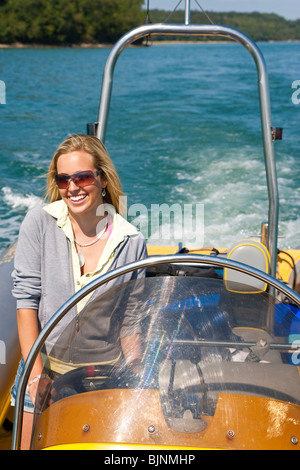 Une belle jeune femme au volant d'un bateau et d'avoir du plaisir. Banque D'Images