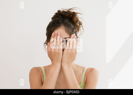 Woman peering par mains Banque D'Images