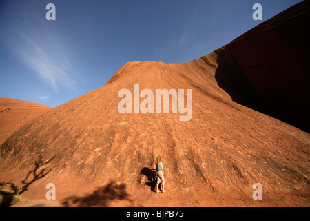 Woman lors de la formation de grès de renommée mondiale, l'Uluru ou Ayers Rock , Territoire du Nord, Australie Banque D'Images