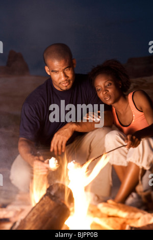 Couple assis en face de camp la nuit Banque D'Images