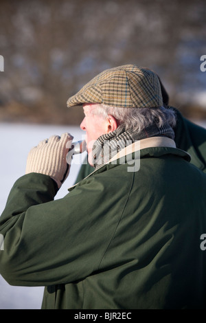 Monsieur âgé de boire du hip flask en hiver Banque D'Images