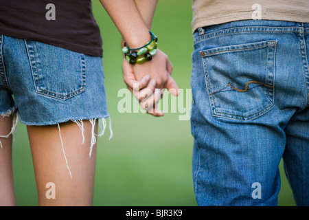Jeune couple en train de marcher sur une pelouse, bras dessus bras dessous Banque D'Images