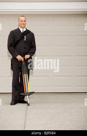 Deux hommes d'affaires avec un autre sur un Pogo Stick Banque D'Images