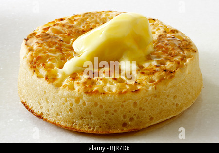 Traditionnel unique crumpet hot buttered close up sur un fond blanc, avec du beurre fondu prêt à manger Banque D'Images