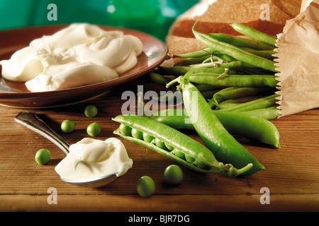 La nourriture reste la vie de petits pois et pois fraîchement cueillis dans le jardin dans les gousses sur une table rustique dans un être de cuisine préparé Banque D'Images