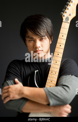 Young man holding guitar, portrait Banque D'Images