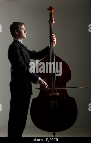 Jeune homme jouant de la contrebasse, studio shot Banque D'Images