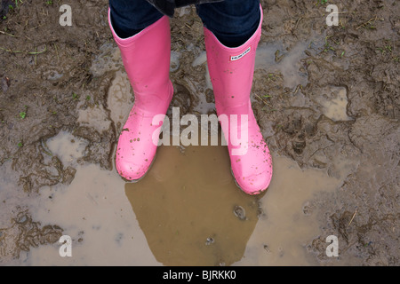 Une paire de rose lumineux Hunter Wellies bottes Wellington () stand de boue-éclaboussa, imperméabilisé dans un coin de campagne flaque. Banque D'Images