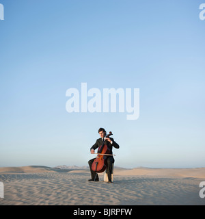 USA, Utah, little Sahara, young man with cello in desert Banque D'Images