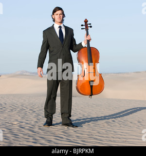 USA, Utah, little Sahara, portrait of young man with cello in desert Banque D'Images