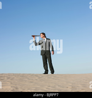 USA, Utah, little Sahara, businessman looking through telescope in desert Banque D'Images