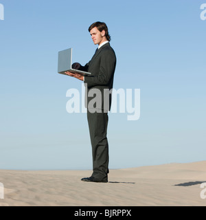 USA, Utah, little Sahara, businessman looking through telescope in desert Banque D'Images