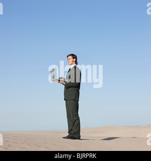 USA, Utah, little Sahara, businessman looking through telescope in desert Banque D'Images