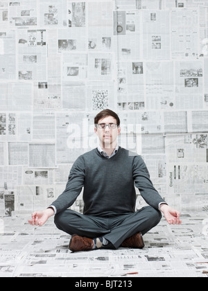 Man practicing yoga in chambre avec des murs couverts de journaux Banque D'Images