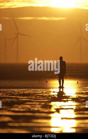 "Un autre endroit" Coucher du Soleil, éoliennes et Antony Gormley sculpture de l'homme Crosby Beach, Merseyside, England, UK Banque D'Images