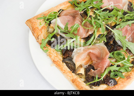 Feuille de Brick pizza garnie de prosciutto, roquette et oignons caramélisés Banque D'Images