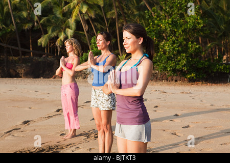 Les femmes pratiquant le yoga sur une plage Banque D'Images