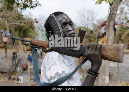 SOUDAN DU SUD, Cuibet, guerrier Dinka, berger avec le visage enduit de cendres posant avec la mitrailleuse Kalachnikov de fabrication soviétique ou russe AK-47 dans un camp de bétail Banque D'Images