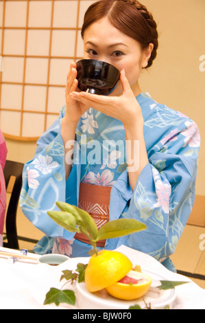 Femme vêtue d'un yukata et de boire la soupe miso Banque D'Images