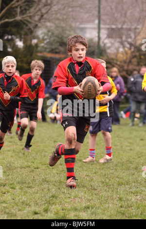 Les jeunes joueurs de rugby Junior en match de compétition club exécutant avec la balle EDITORIAL UTILISEZ UNIQUEMENT Banque D'Images