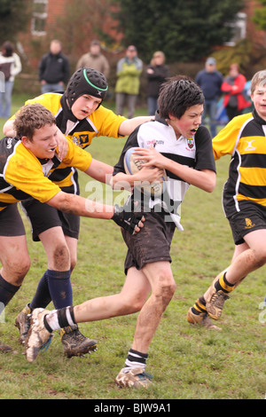 Les jeunes joueurs de rugby Junior en match de compétition club exécutant avec la balle abordées uniquement ÉDITORIALE Banque D'Images