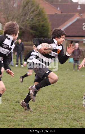 Les jeunes joueurs de rugby Junior en match de compétition club exécutant avec la balle EDITORIAL UTILISEZ UNIQUEMENT Banque D'Images