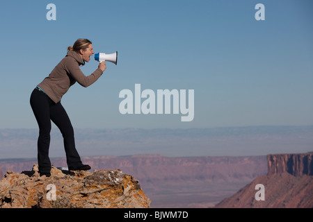 Woman yelling into megaphone en haut du canyon Banque D'Images