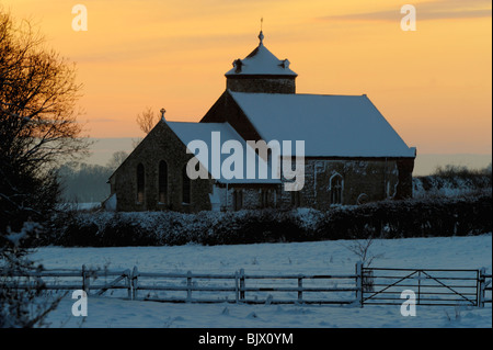 L'église St Andrews peu vu de ronflement à travers champs au coucher du soleil dans la neige Banque D'Images