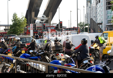 Voitures, camionnettes, les cyclistes et les motos d'attente à un feu rouge. Il y a une station de métro et bus de Londres derrière. Banque D'Images