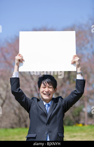 Young businessman holding blank placard Banque D'Images