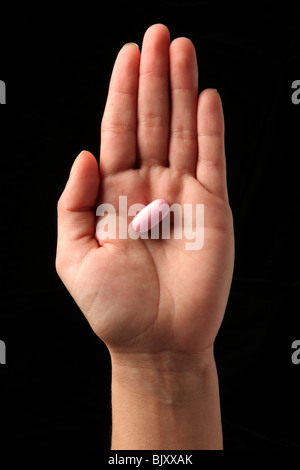 Une femme woman's hand holding une pilule dans la paume de sa main Banque D'Images