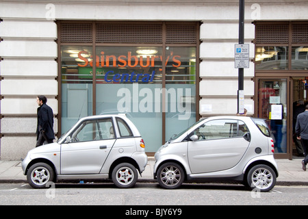 Deux petites voitures électriques, G-Wiz voiture Smart essence et le partage d'un seul espace de stationnement dans le quartier de Mayfair à Londres. Banque D'Images