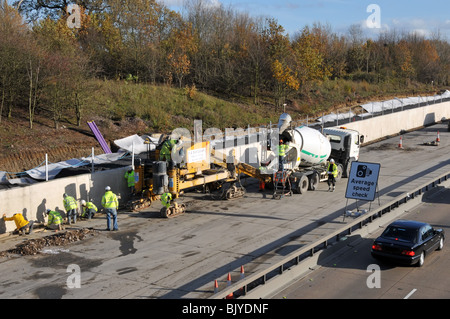 Autoroute M25 l'élargissement à 4 voies sous forme de pavage en béton et les camions de la machine Banque D'Images