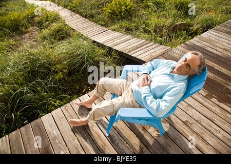 Senior man sitting on chair sieste au soleil Banque D'Images