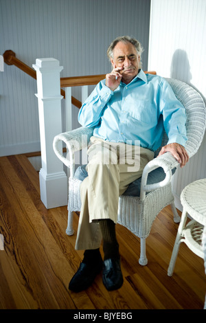 Senior woman relaxing in wicker chair blanche en haut de l'escalier Banque D'Images