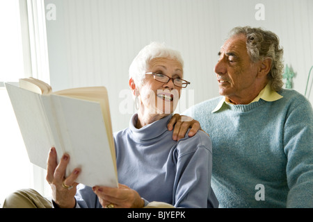 Senior couple sitting on bed reading book Banque D'Images