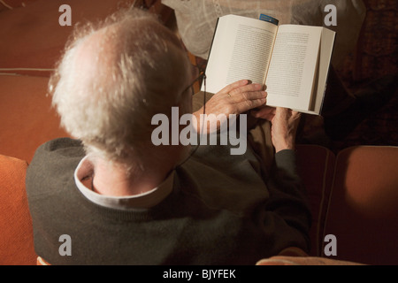 Man dans un canapé-lit un livre. Banque D'Images