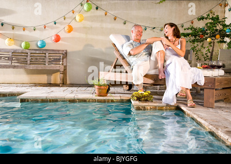 Affectueux mature couple laughing together pool Banque D'Images