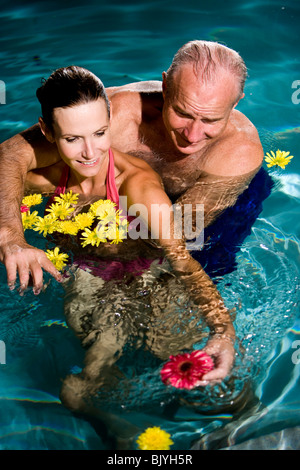 Couple romantique dans la piscine entourée de fleurs flottant Banque D'Images